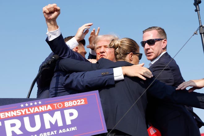 The Republican presidential candidate, former President Donald Trump, raised a fist through the scrum of Secret Service as they hurried him off the stage.