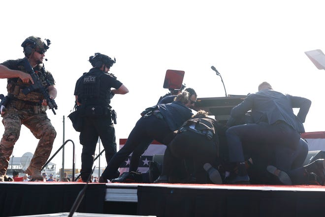 Secret Service officers cover Trump in response to the sound of shots that ripped through the rally as the Republican presidential candidate spoke.