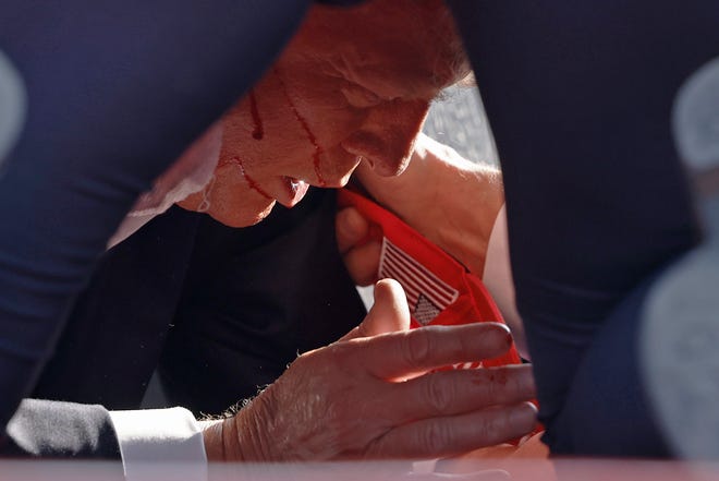 Republican presidential candidate former President Donald Trump seen, with blood dripping from his ear, inside the circle of Secret Service cover on the floor of the stage at the rally in Butler, Pennsylvania.