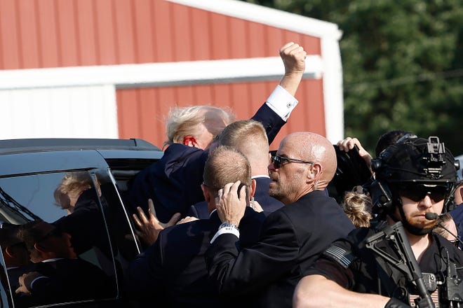 Republican presidential candidate former President Donald Trump again pumps his fist as he is rushed into car after the shooting at a rally on July 13, 2024, in Butler, Pennsylvania.