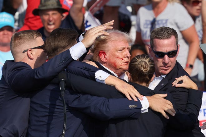 The cluster of Secret Service officers began to move Trump from the stage.