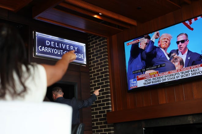 People watch news of a possible assassination attempt on Republican presidential candidate and former President Donald Trump at a campaign rally at Carson's on July 13, 2024, in Milwaukee, Wisconsin. The former president was rushed off the stage by Secret Service after being injured during the incident.