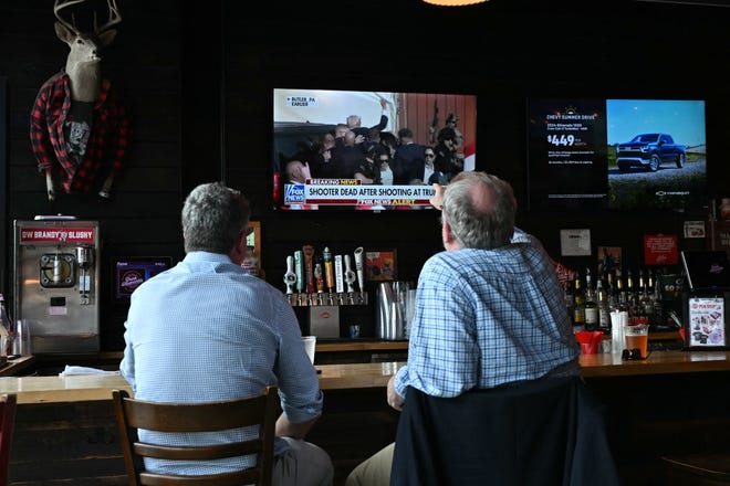 People watch the news of the shooting at the Trump rally on television inside a bar on July 13, 2024, in Milwaukee, Wisconsin.