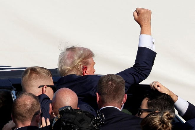 Republican presidential candidate and former President Donald Trump gestures as he is assisted by the Secret Service after gunfire rang out during a campaign rally at the Butler Farm Show in Butler, Pennsylvania, on July 13, 2024.