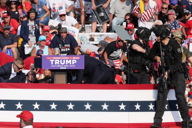 Republican presidential candidate and former President Donald Trump is assisted by Secret Service personnel after gunfire rang out during a campaign rally at the Butler Farm Show in Butler, Pennsylvania, on July 13, 2024.