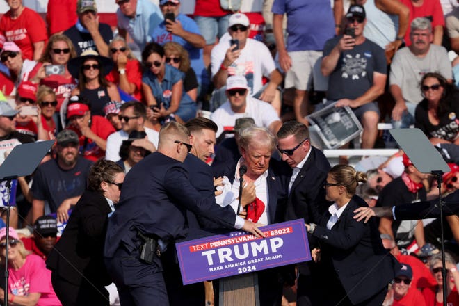 Former President Donald Trump is assisted by Secret Service personnel after gunfire rang out during his reelection campaign rally in Butler, Pa., on July 13, 2024.