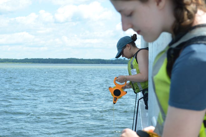 UVM Agroecology Fellows Nora Beer and Anna Hoppe give a demonstration of the Secchi, a water clarity testing device, aboard the Marcelle Melosira July 18, 2024.