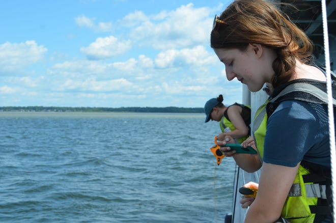 UVM Agroecology Fellows Nora Beer and Anna Hoppe give a demonstration of the Secchi, a water clarity testing device, aboard the Marcelle Melosira July 18, 2024.