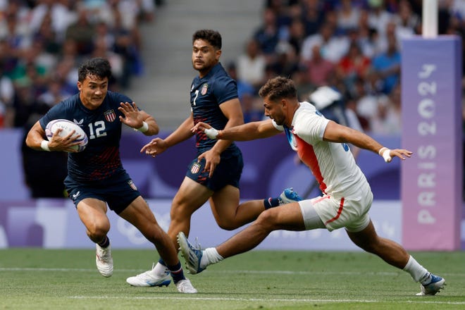 Team United States back Lucas Lacamp (12) runs the ball against France in a rugby Group C match during the Paris 2024 Olympic Summer Games at Stade de France on July 24, 2024.