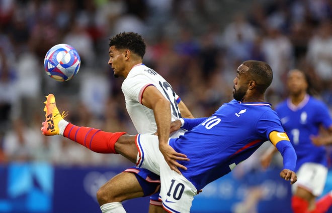 Alexandre Lacazette of France in action with Miles Robinson of United States during a men's Group A football match on July 24, 2024, during the Paris 2024 Olympic Summer Games at Orange Velodrome in Marseille.